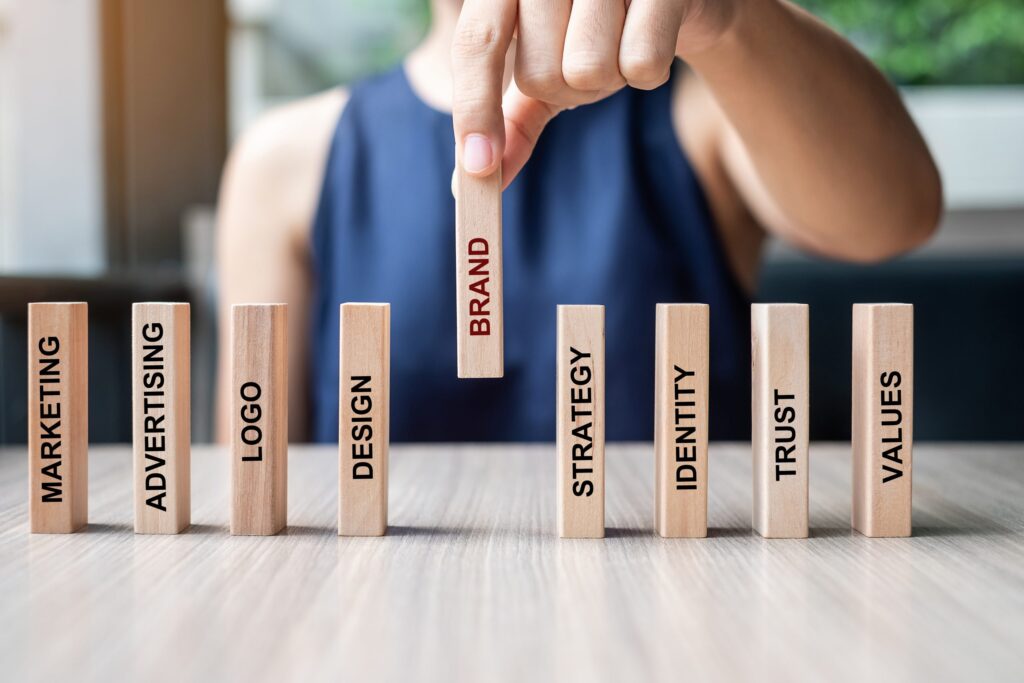 Businesswoman hand placing or pulling wooden Dominoes with BRAND