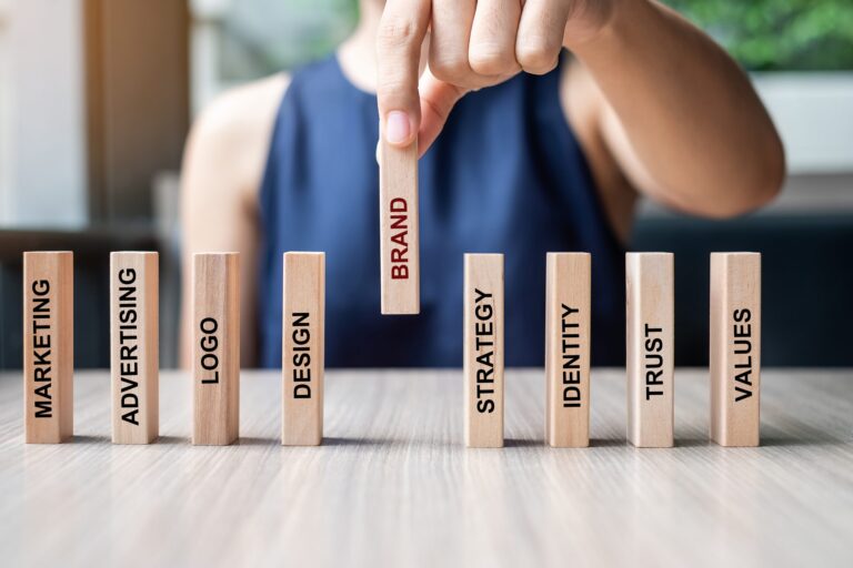 Businesswoman hand placing or pulling wooden Dominoes with BRAND