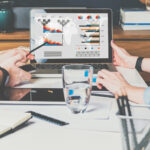 Businessman and businesswoman sitting at table in front of laptop and working.Graphs,charts and diagrams on PC screen.